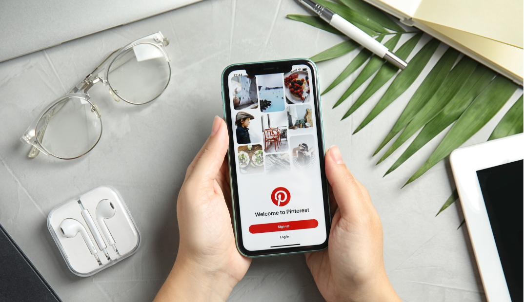 A person holding a mobile phone with an image of a Pinterest page open on it.